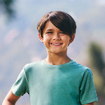 A young boy with brown hair wearing a green t-shirt, smiling