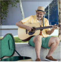 A 74 year old male DUPIXENT® (dupilumab) patient smiling and playing the guitar