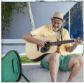 A 74 year old male DUPIXENT® (dupilumab) patient smiling and playing the guitar