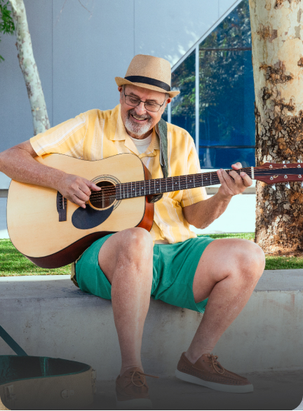 Roger, a 74 year old male DUPIXENT® (dupilumab) patient smiling and playing the guitar